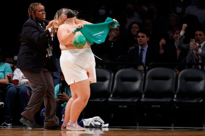 Security appears to be pulling one protester by the hair during the demonstration at the WNBA game.