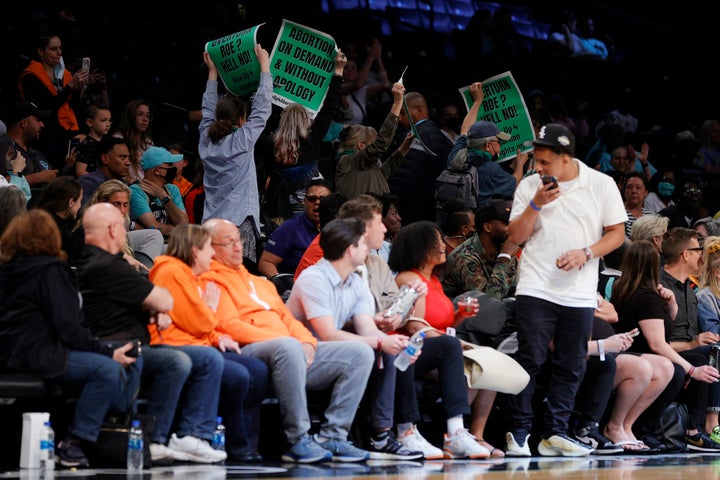 Spectators held up signs while protesters rushed the court in the abortion rights demonstration.