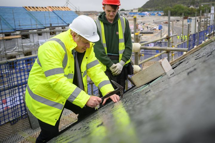 Boris Johnson is shown how to fit roofing tiles during a visit to the West Carclaze Garden Village housing development in Cornwall.