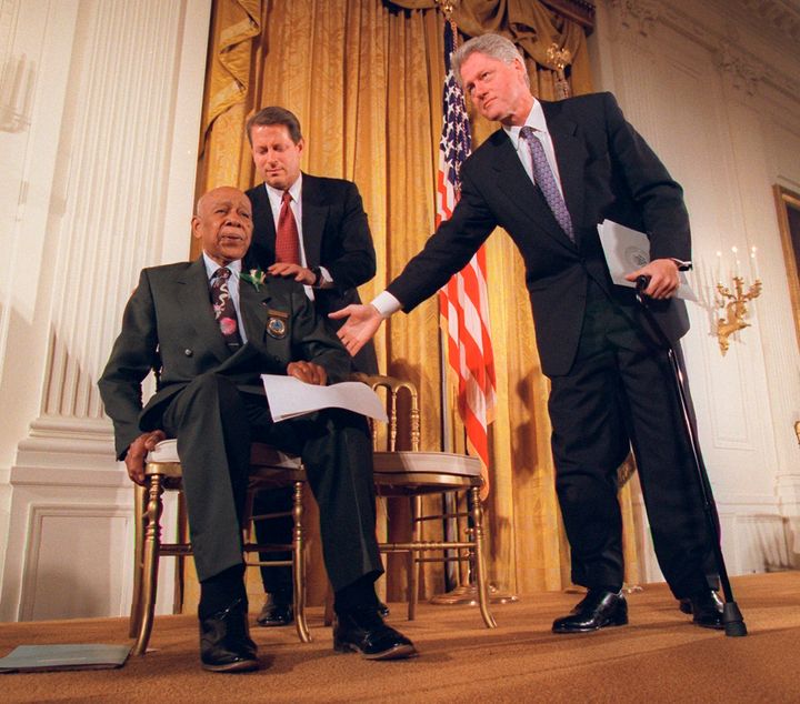 FILE - President Clinton and Vice President Al Gore, back, help Herman Shaw, 94, a Tuskegee Syphilis Study victim, during a news conference in 1997.