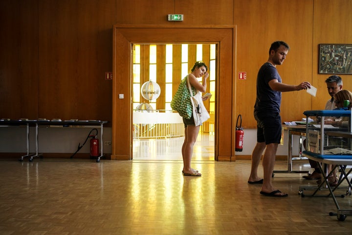 A voter submits his ballot in the first round of the French parliamentary election in Lyon, central France, Sunday June 12, 2022. Voters are choosing lawmakers as President Emmanuel Macron seeks to secure his majority while under growing threat from a leftist coalition. (AP Photo/Laurent Cipriani)