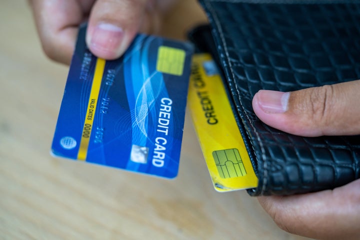 Cropped image of businessman giving credit card from wallet at desk