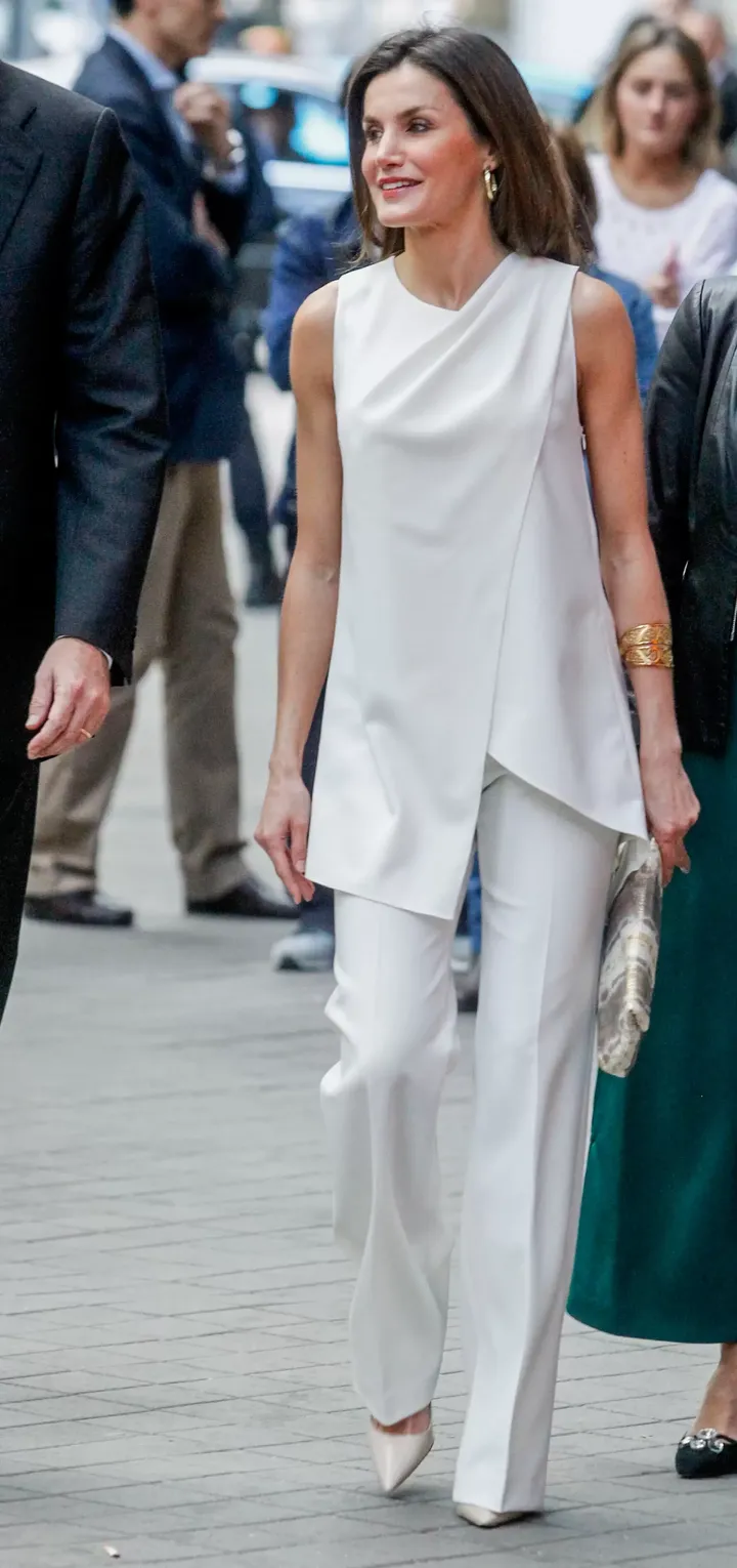 Η βασίλισσα της Ισπανίας, Λετίθια Ορτίθ Ροκασολάνο, με λευκό ασύμμετρο τοπ χωρίς ώμους, συνδυασμένο με ολόλευκη καμπάνα με τσάκιση και ανατρεπιτκό ιβουάρ τσαντάκι τύπου κλατσ.
