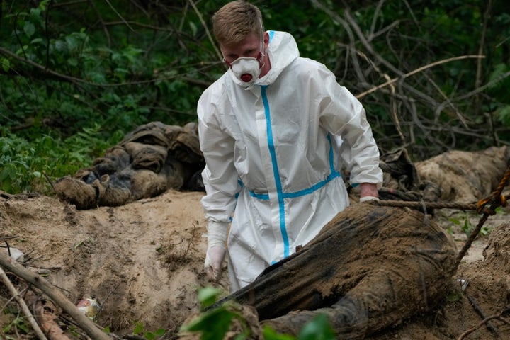 Un miembro de un equipo de exhumación labora en una fosa común cerca de Bucha.