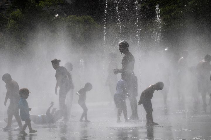 Personas refrescándose en una fuente, en Madrid.