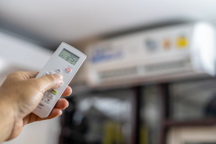Close up hand adjusting temperature of air conditioner.