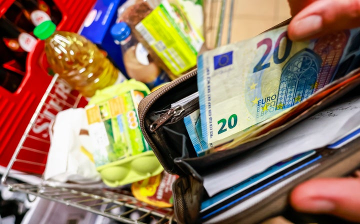Una persona retirando un billete de la cartera mientras hace la compra.