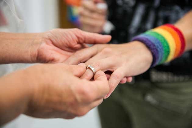 アメリカ最高裁判所で「結婚の平等は憲法が認めた権利」という判決が言い渡された後、カリフォルニア州ロサンゼルスの郡登録記録官事務所でパートナーの指に結婚指輪をはめたカップル（2015年6月26日）
