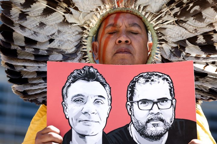 A member of the Articulation of Indigenous Peoples of Brazil (APIB) holds the image of missing British journalist Dom Phillips and Brazilian Indigenous affairs specialist Bruno Pereira during a protest in Europe. Brazil's police confirmed Wednesday that someone had confessed to killing the two men in a remote region of the Amazon rainforest.