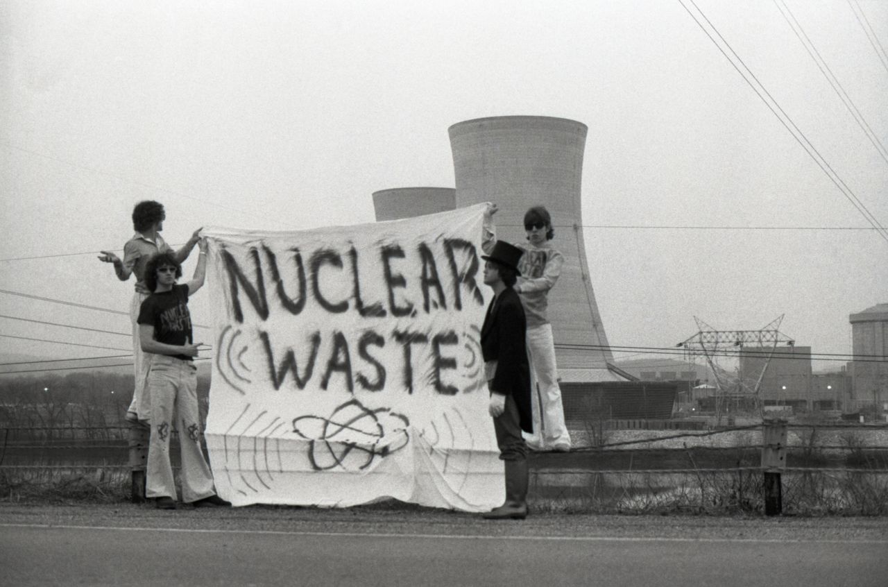 With one man dressed in an undertaker's outfit, a group of people unfurl a protest banner in front of the cooling towers at the Three Mile Island nuclear plant near Harrisburg, Pennsylvania, on April 1, 1979.
