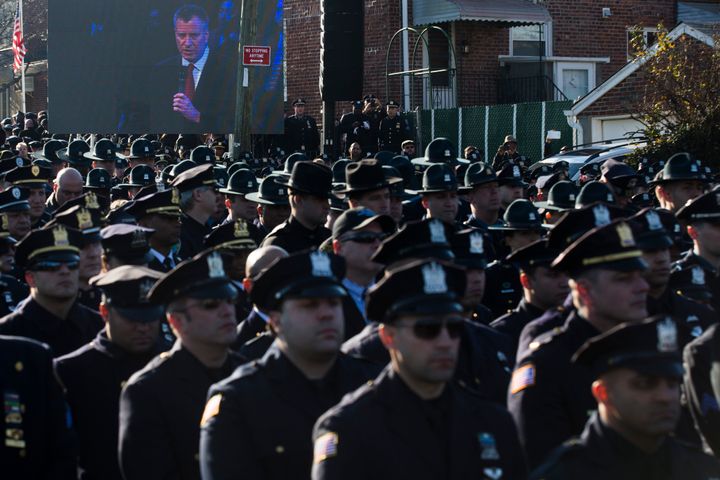 Police officers turn their backs as then-New York City Mayor Bill de Blasio speaks at the funeral of two slain NYPD officers in December 2014.