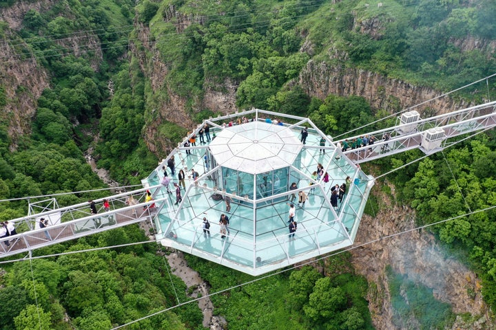 ダシュバシ峡谷に建設されたガラス製の吊り橋を渡る人々。ダイヤモンド型のカフェが見える（2022年6月14日撮影）