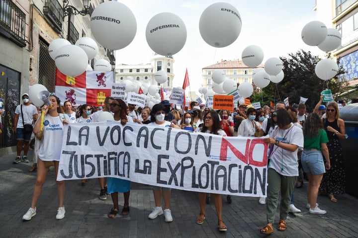 MADRID, SPAIN - JUNE 18: Several people hold a banner reading: 'Vocation does not justify exploitation' during a demonstration against the "abandonment" of healthcare, on 18 June, 2022 in Madrid, Spain. The march, called by Unidad Enfermera, aims to denounce the "serious neglect" suffered by the healthcare system. Unidad Enfermera is an alliance made up of different organizations and associations that defend the interests of the 325,000 patients and nurses in the country. Through this concentration, the platform wants to make clear to the public administrations the need to prioritize the improvement of the health system and demands measures to improve the professional, working, university, scientific and managerial conditions of the sector. (Photo By Gustavo Valiente/Europa Press via Getty Images)