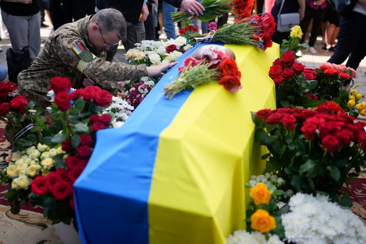 A solider kneels at activist and soldier Roman Ratushnyi's coffin during the memorial service in Kyiv, Ukraine, on June 18. Ratushnyi died in a battle near Izyum, where Russian and Ukrainian troops are fighting for control of the area.