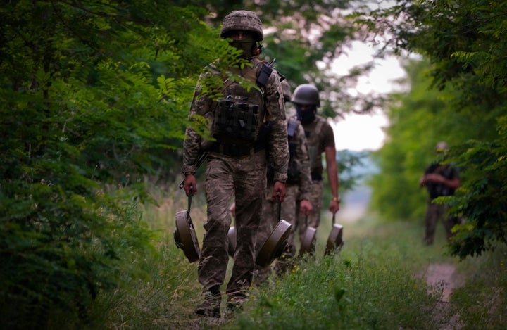 A Ukraine special operations unit carries anti-tank mines to bury on a forest track to prevent Russian troops from advancing toward their trenches in the Donetsk region, Ukraine, on June 14.