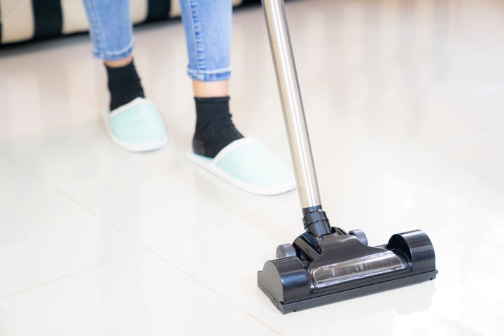 Part of woman vacuuming living room at home