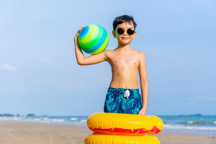 Portrait of a playful boy holding the sports ball on the beach. summer vacation and holiday concept.