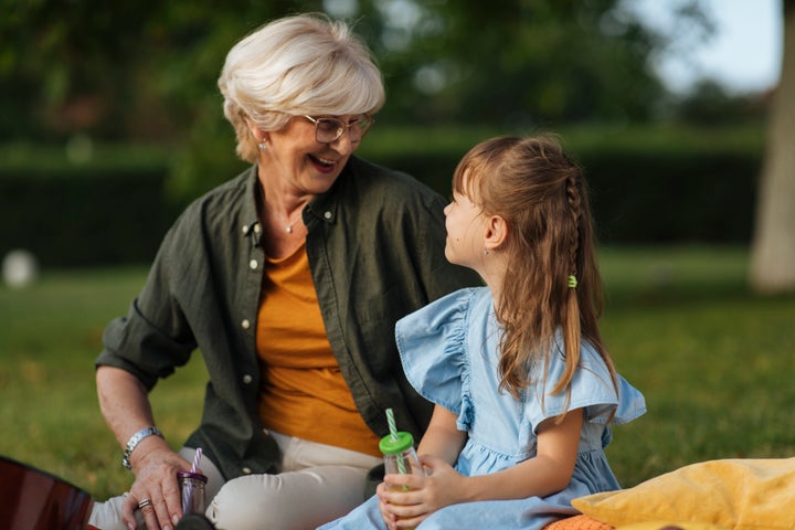 Happy grandmother and little granddaughter having fun together in park