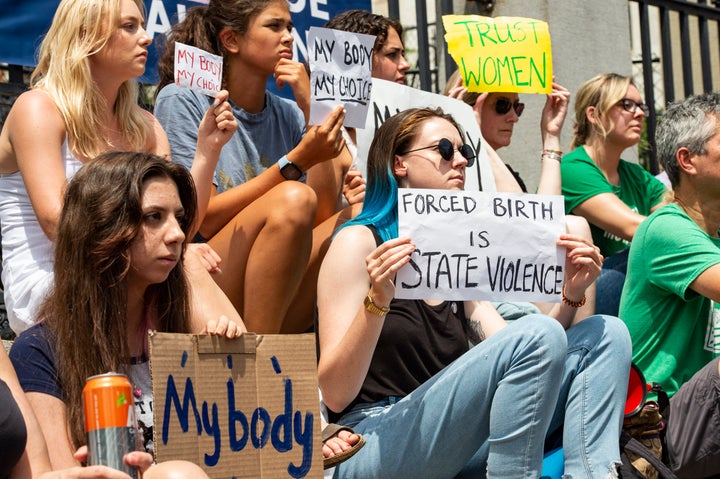 Demonstrators hold signs during a rally at the Massachusetts State House in Boston.