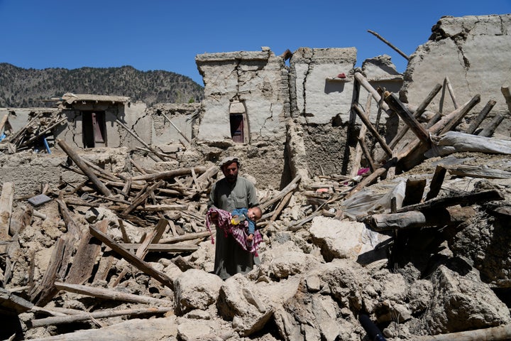 An Afghan man carries his child amid destruction after the earthquake on Friday.