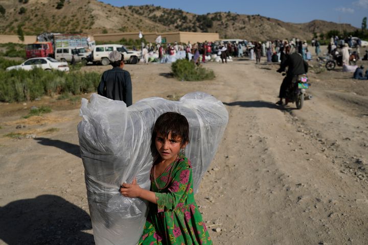 An Afghan girl carries a donated mattress.
