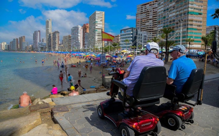 Dos personas miran una de las playas de Benidorm.