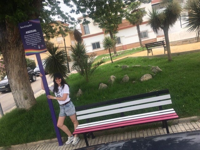 Olivia Ávila, junto a un banco con los colores de la bandera asexual.