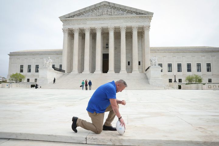 Former Bremerton High School assistant football coach Joe Kennedy takes a knee in front of the U.S. Supreme Court after the court heard his legal case, Kennedy vs. Bremerton School District.