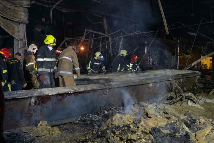 Ukrainian State Emergency Service firefighters to take away debris at a shopping center burned after a rocket attack in Kremenchuk, Ukraine, on June 28, 2022.