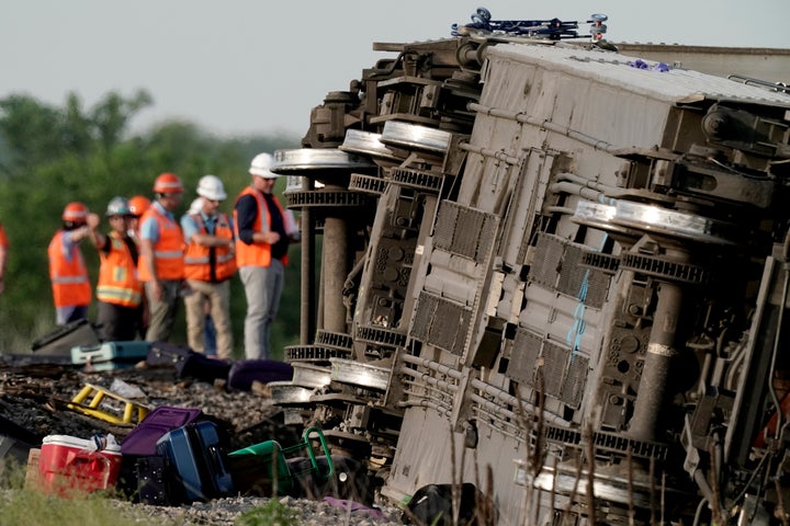 Workers inspect the scene of an Amtrak train which derailed after striking a dump truck on June 27, 2022, near Mendon, Mo.