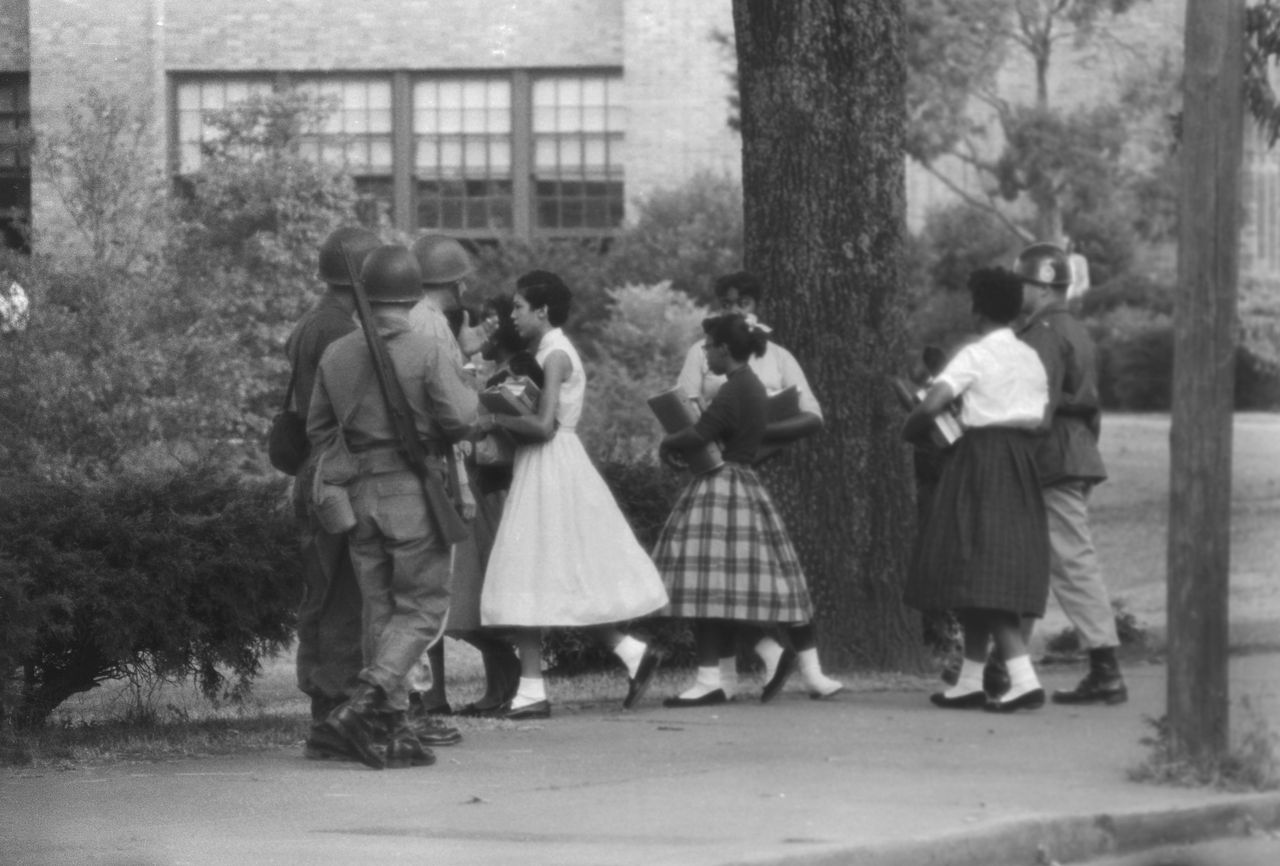 The group of nine African American students walk past members of the National Guard as they use a side door to enter Central High School in Little Rock, Arkansas.