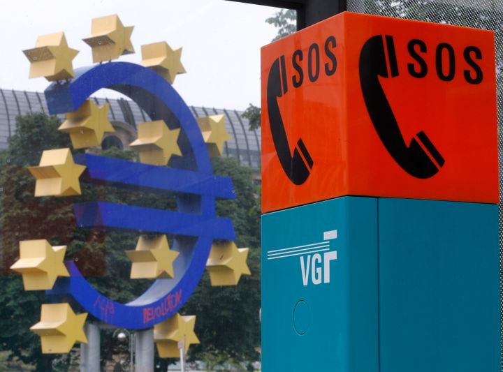 Τηλέφωνο για χρήση σε περίπτωση έκτακτης ανάγκης σε μία στάση λεωφορείου μπροστά στο γλυπτό με το σύμβολο του ευρώ, έξω από την έδρα της ΕΚΤ στην Γερμανία. Φραγκφούρτη 11 Ιουνίου 2013. (AP Photo/Michael Probst)