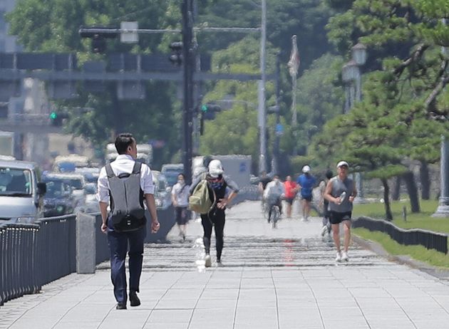 強い日差しの中、皇居沿いの道を行き交う人たち＝6月29日午前、東京都千代田区