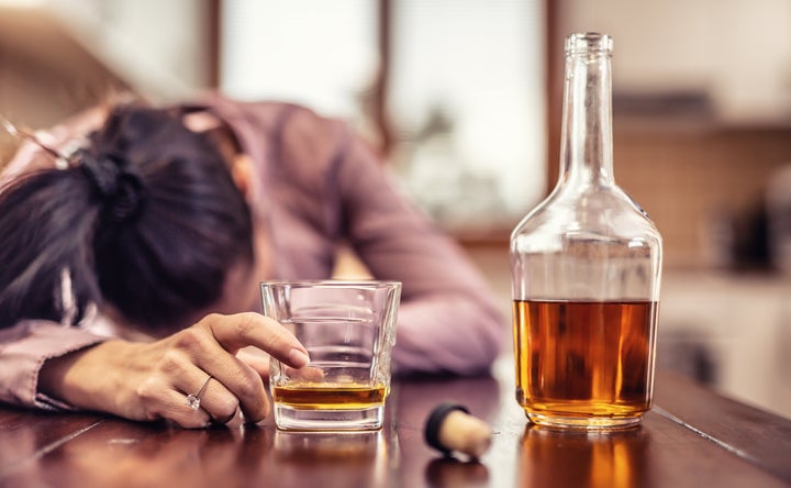 Mujer con una botella y un vaso de alcohol.