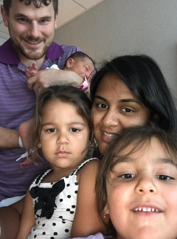 The author, her spouse, their two daughters, and newborn son posing at the hospital for their first family selfie after she gave birth.