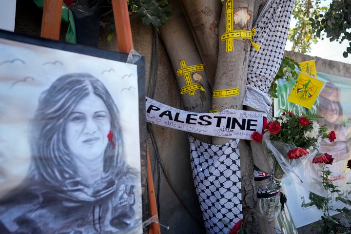 Yellow tape marks bullet holes on a tree and a portrait and flowers create a makeshift memorial at the site where Palestinian-American Al-Jazeera journalist Shireen Abu Akleh was shot and killed in the West Bank city of Jenin, May 19, 2022.