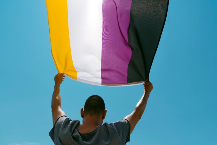 Persona sujetando la bandera no binaria.