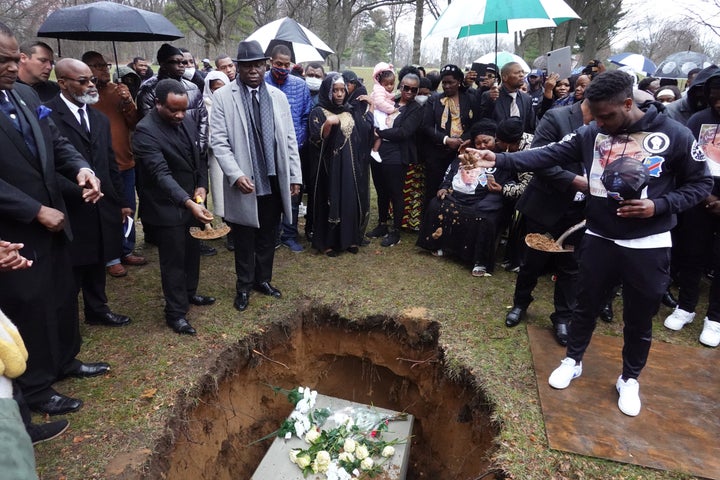 Mourners toss dirt into the grave of Patrick Lyoya as he is laid to rest at Resurrection Cemetery on April 22, 2022, in Wyoming, Michigan.