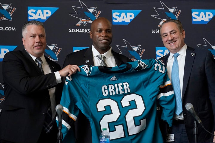 Mike Grier, middle, poses for photos with San Jose Sharks assistant general manager Joe Will, left, and president Jonathan Becher in San Jose, California on Tuesday.