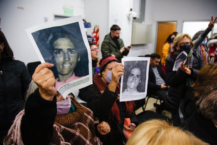 Varias personas sostienen imágenes de personas desaparecidas durante la dictadura militar en Argentina.