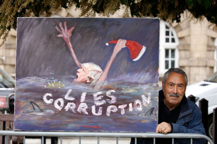 6 Ιουνίου 2022. Ενας καλλιτέχνης κρατά σκίτσο με τις λέξεις "Ψέματα" και "Διαφθορά" έξω από την Βουλή των Κοινοτήτων στο Λονδίνο. Ο Τζόνσον πνίγεται... (AP Photo/David Cliff)