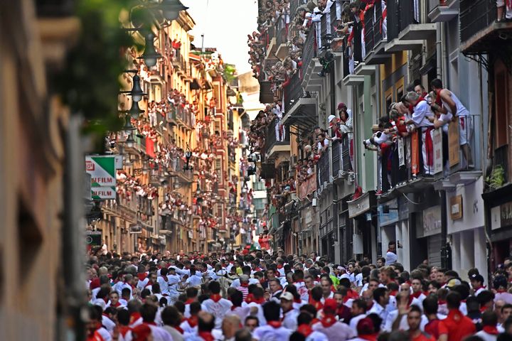 People run through the streets ahead of fighting bulls and steers during the first day of the running of the bulls at the San Fermin Festival in Pamplona, northern Spain, on July 7, 2022. 