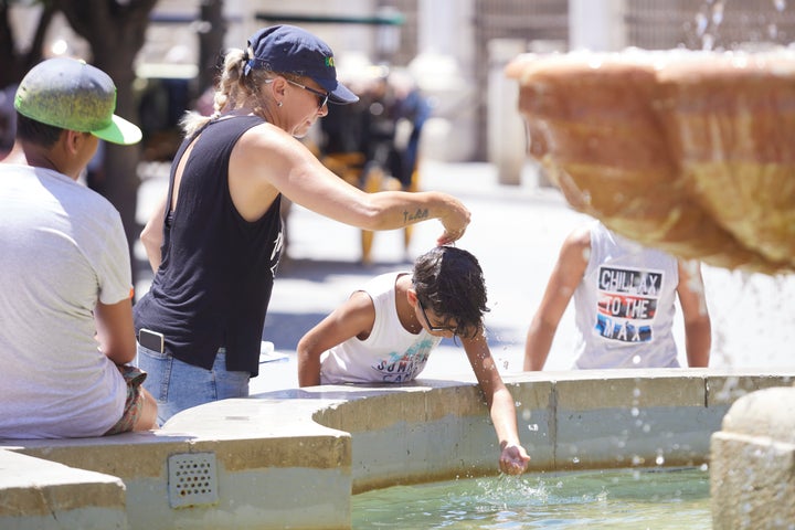Una familia se refresca, como puede, en una fuente de Sevilla