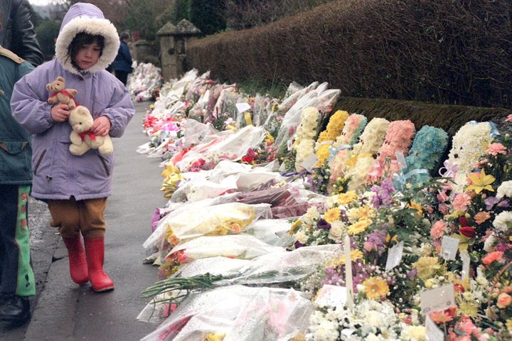 A child looks at the floral tributes outside Dunblane primary school after a gunman killed 16 children and their teacher in March 1996.
