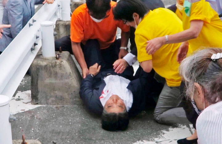 In this image from a video, Japan’s former Prime Minister Shinzo Abe, center, is attended on the ground in Nara, western Japan, on July 8, 2022.