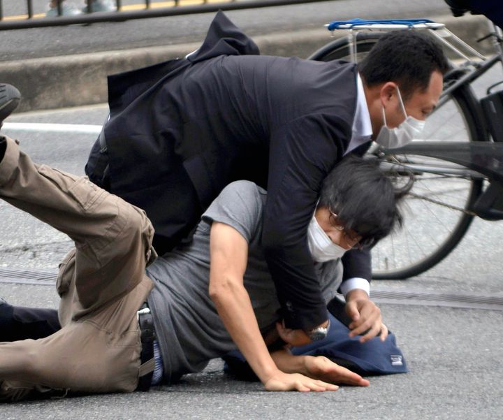 Tetsuya Yamagami, bottom, is detained near the site of gunshots in Nara Prefecture, western Japan, on July 8, 2022.