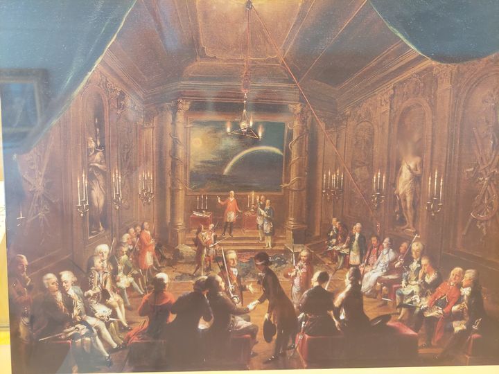 Ζωγραφική αναπαράσταση μουσικής βραδιάς σε σαλόνι εποχής με τον Μότσαρτ πιθανότατα στο κέντρο.