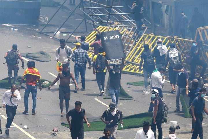 Protestors run after police used tear gas to disperse them in Colombo, Sri Lanka, Saturday, July 9, 2022.