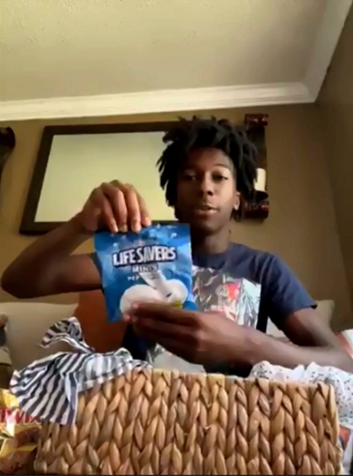 During a Zoom call, Friday, July 8, 2022, Corion Evans poses with candy gifted to him from the motorists he saved after their car drove off the Interstate 10 boat launch and into the Pascagoula River, in Mississippi, early Sunday, July 3. (AP Photo/Carrie Antlfinger)