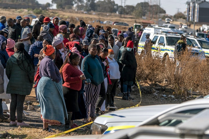 People look on at the scene of an overnight bar shooting in Soweto, South Africa, Sunday July 10, 2022. (AP Photo/Shiraaz Mohamed)